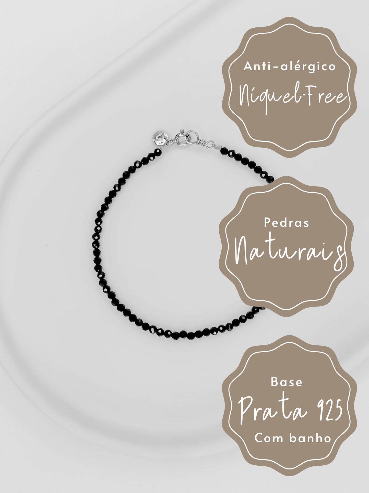 Foto preta e branca de Pulseira Rasa produzida com esferas lapidadas do cristal espinelio medindo aproximadamente 2mm cada com tamanho de 16 cm e fecho boia em prata apoiada em uma bandeja de cerâmica branca e fundo branco.