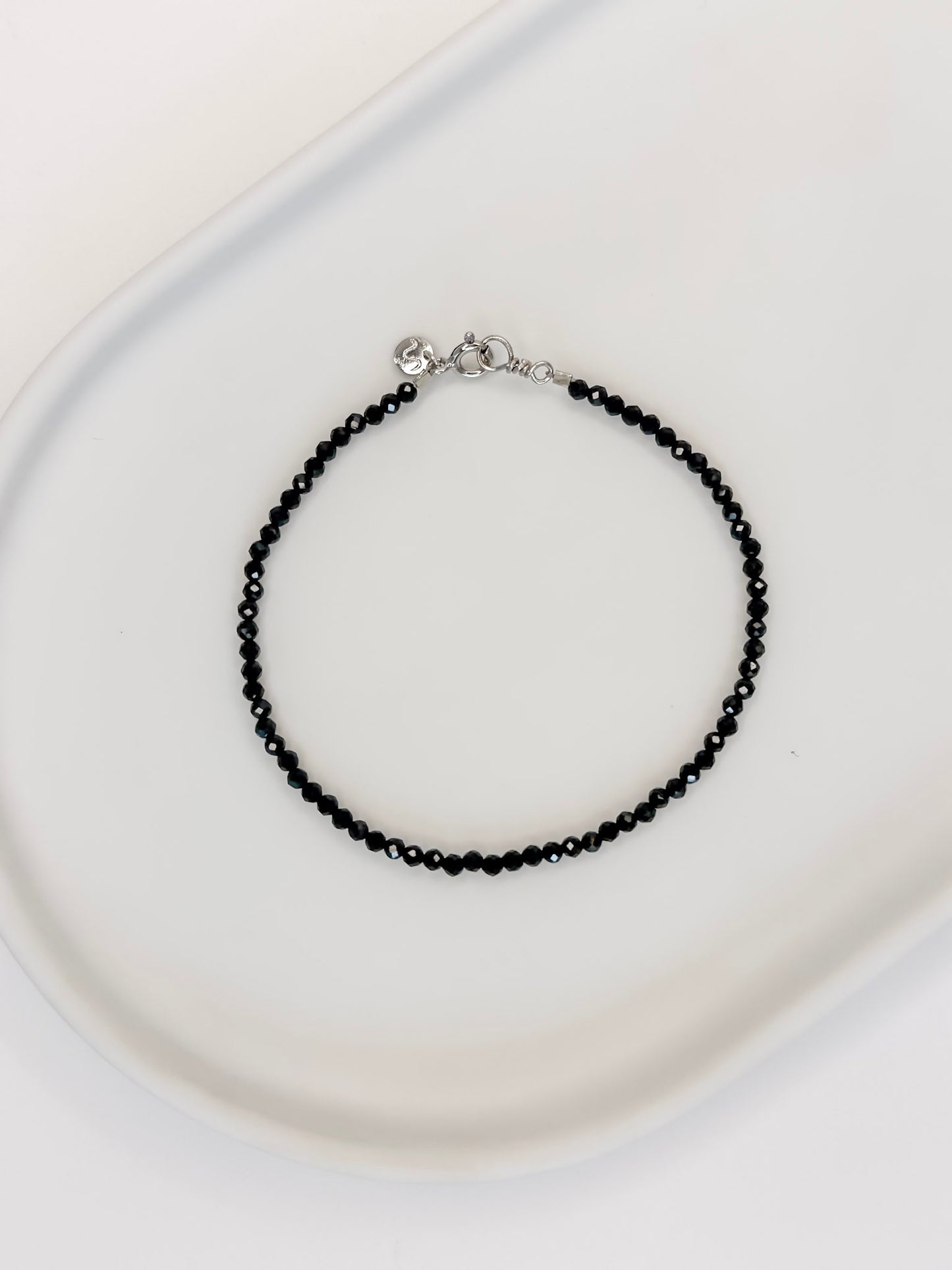 Pulseira produzida com esferas facetadas de espinelio natural medindo aproximadamente 2mm cada, com fecho em prata 925, apoiado em bandeja de ceramica branca e fundo branco.