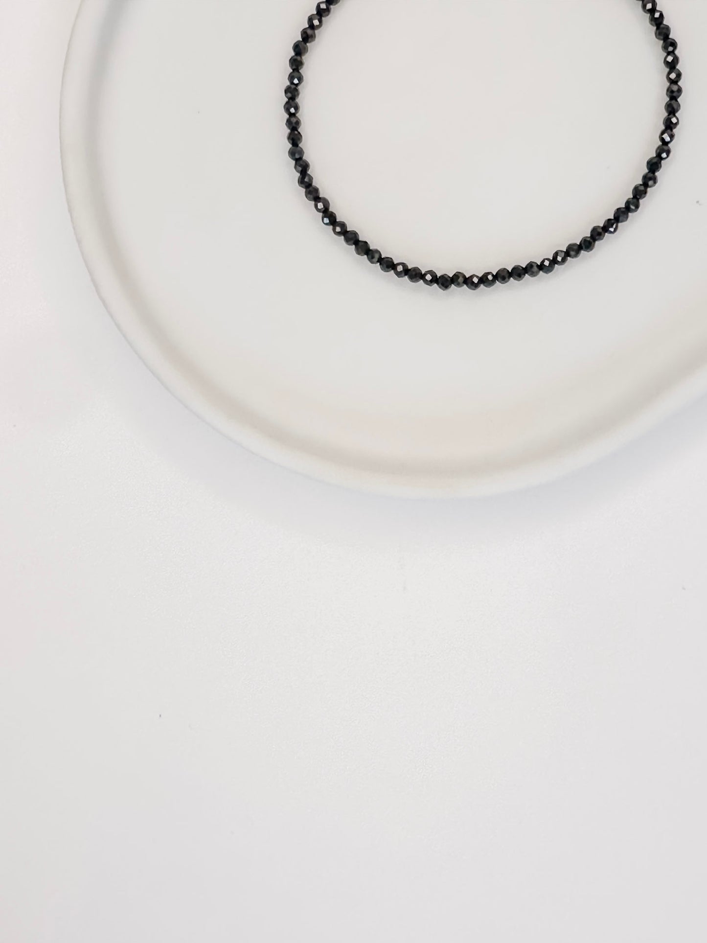 Pulseira produzida com esferas facetadas de espinelio natural medindo aproximadamente 2mm cada, com fecho em prata 925, apoiado em bandeja de ceramica branca e fundo branco.