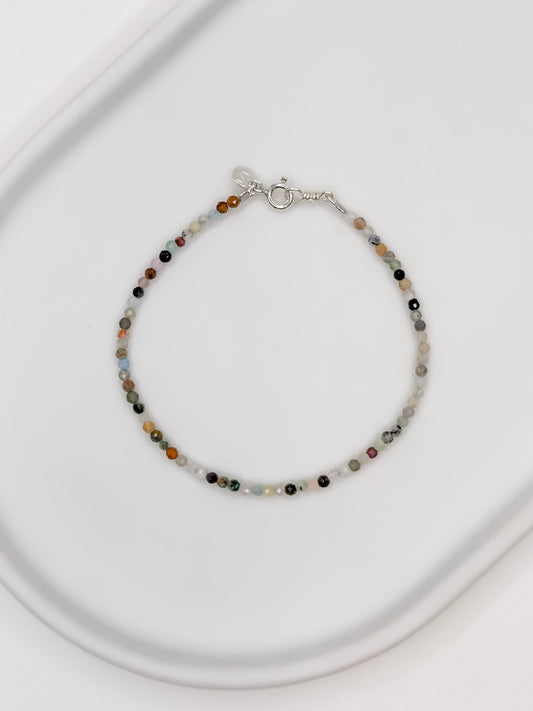 Pulseira com mix de cristais em esferas facetadas de 2 mm cada com fecho boia em prata apoiada em bandeja de ceramica branca.
