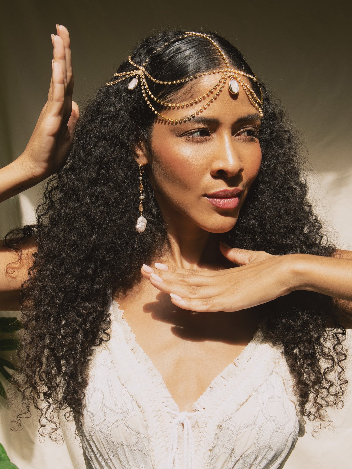 Mulher negra com cabelos longos veste headpiece e brincos longos com perola barroca e topazio imperial